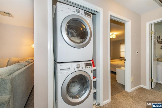 washroom featuring visible vents, baseboards, stacked washer and clothes dryer, laundry area, and carpet flooring