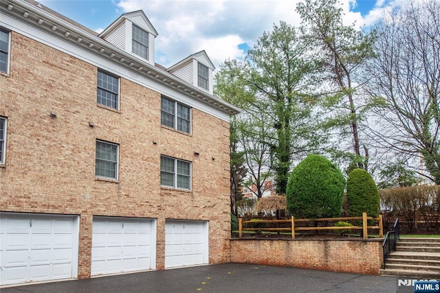 view of home's exterior with brick siding, an attached garage, and aphalt driveway
