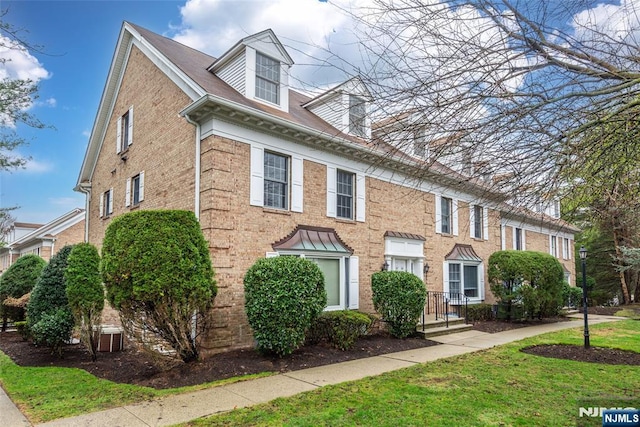 view of front facade with brick siding and a front lawn