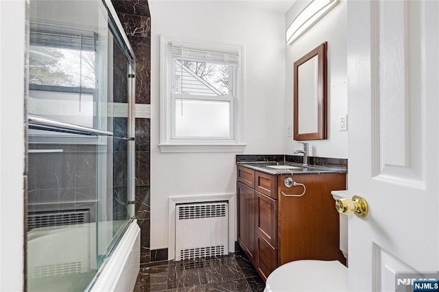 bathroom featuring toilet, radiator, marble finish floor, vanity, and enclosed tub / shower combo