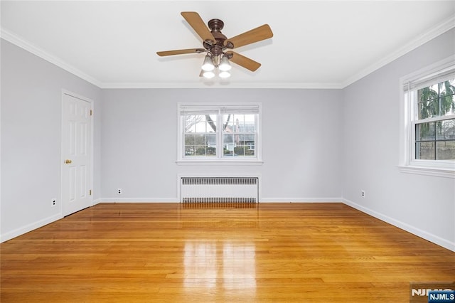 unfurnished room with radiator, light wood finished floors, crown molding, and baseboards