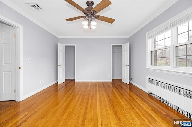unfurnished bedroom featuring radiator, light wood finished floors, multiple windows, and visible vents
