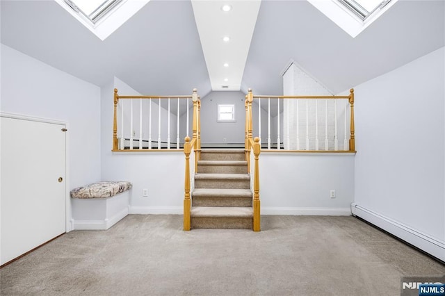 additional living space with carpet flooring, baseboards, vaulted ceiling with skylight, baseboard heating, and stairway