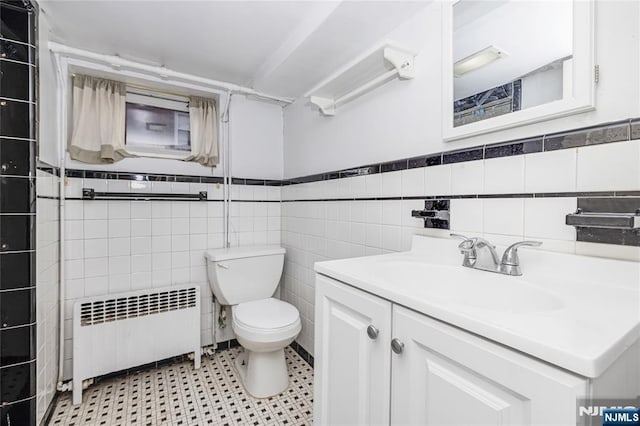 bathroom with a wainscoted wall, toilet, tile walls, radiator heating unit, and vanity