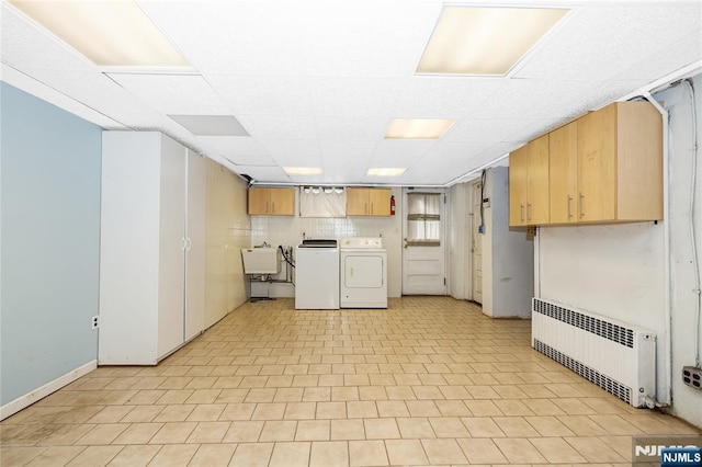 interior space featuring radiator heating unit, a sink, washer and clothes dryer, and cabinet space