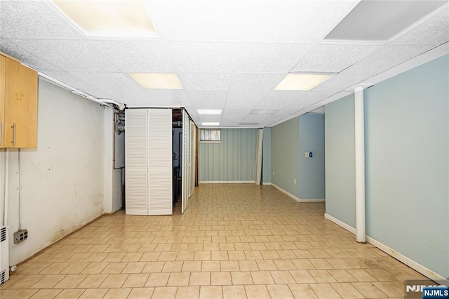 below grade area with baseboards and a drop ceiling