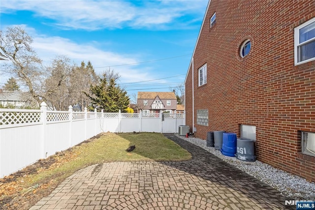 view of yard with a patio area, a fenced backyard, and central air condition unit