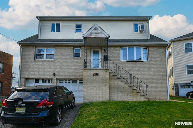 multi unit property featuring an attached garage, brick siding, a front lawn, and aphalt driveway