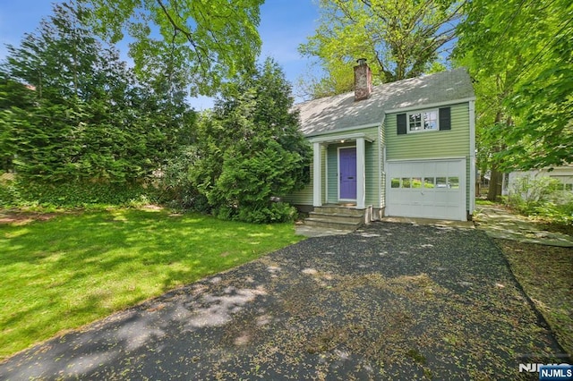 view of front of house with a chimney, asphalt driveway, a front lawn, and roof with shingles