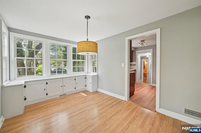 unfurnished dining area with light wood finished floors and baseboards