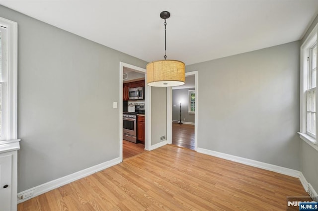 unfurnished dining area featuring light wood-style flooring and baseboards