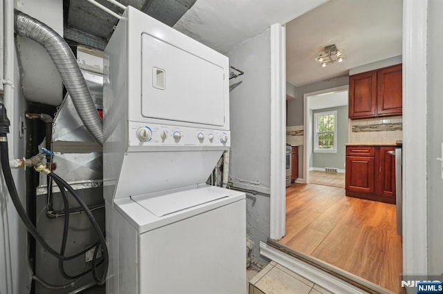 clothes washing area featuring estacked washer and dryer and light wood-type flooring