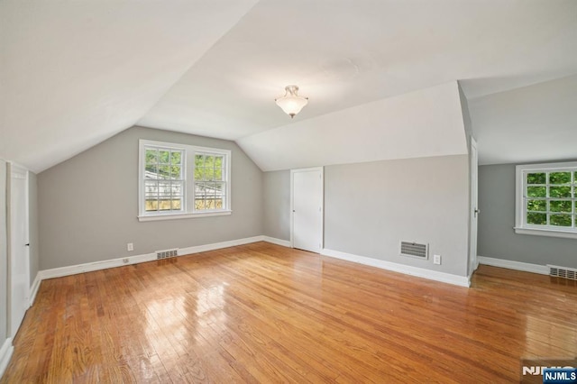 additional living space featuring light wood finished floors, vaulted ceiling, and baseboards