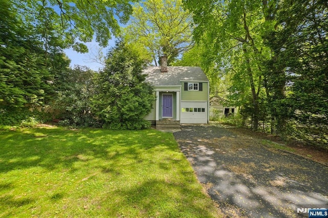 view of front of house with driveway, a chimney, a front lawn, and a garage
