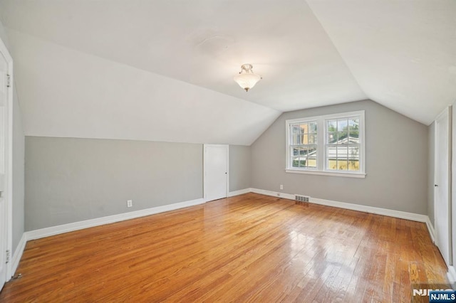 bonus room with light wood finished floors, lofted ceiling, and baseboards
