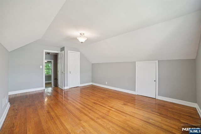additional living space featuring lofted ceiling, light wood-type flooring, and baseboards