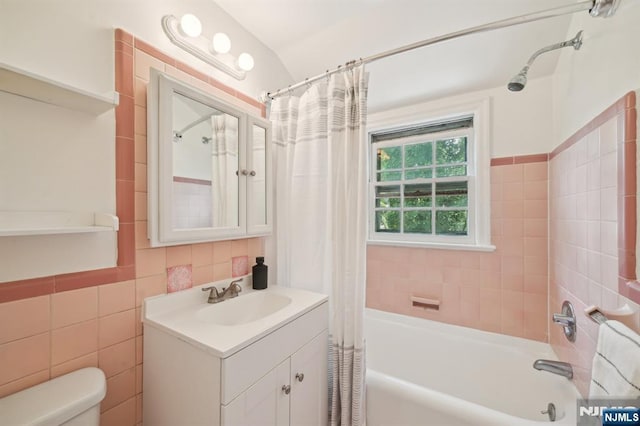 full bath with toilet, shower / tub combo, vanity, and tile walls