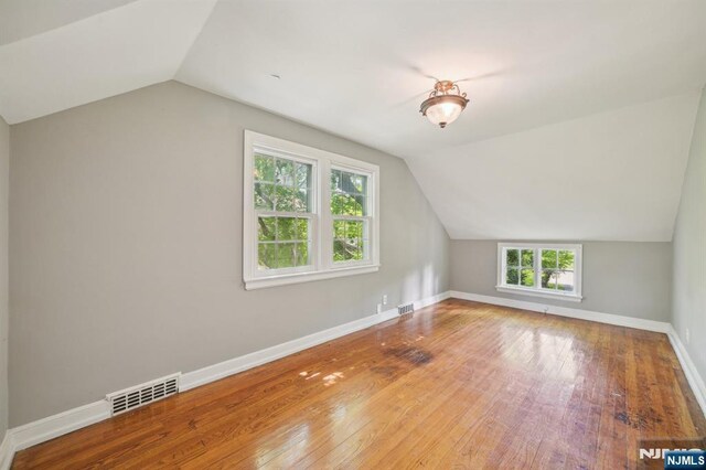 additional living space with lofted ceiling, wood-type flooring, and baseboards