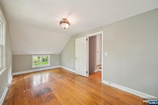 bonus room featuring lofted ceiling, baseboards, and light wood-style flooring