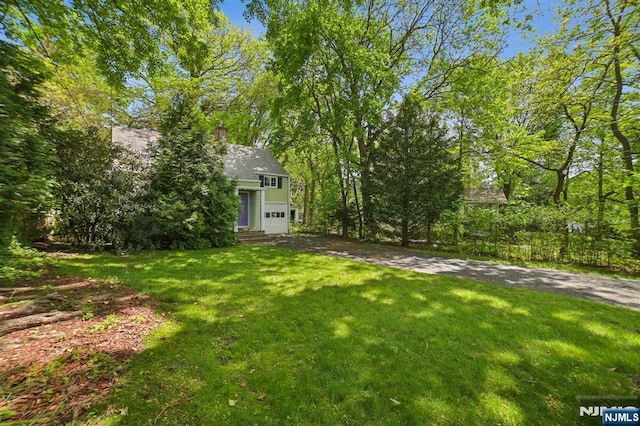 view of grassy yard featuring a garage and driveway