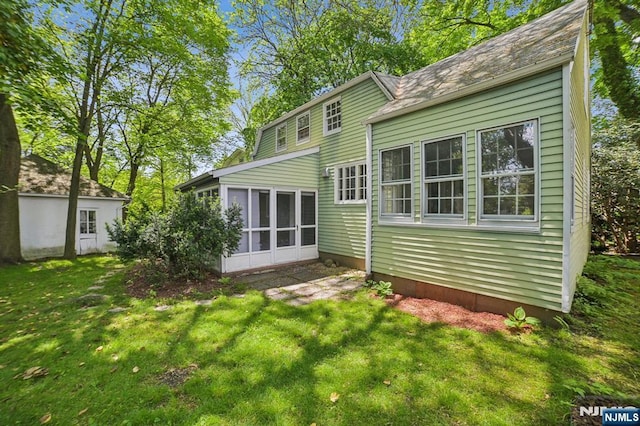 rear view of house featuring a sunroom and a yard