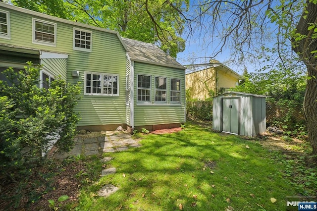 rear view of house with a storage unit, a lawn, and an outbuilding