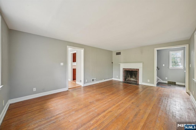 unfurnished living room with a fireplace, light wood-type flooring, and baseboards
