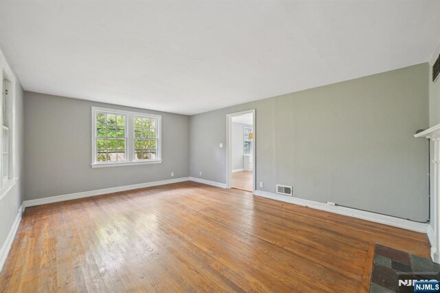 unfurnished living room featuring wood-type flooring and baseboards
