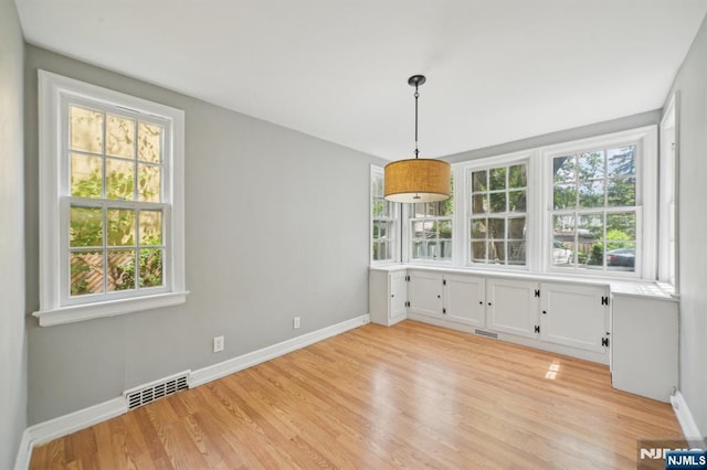 unfurnished dining area with baseboards and light wood-style floors
