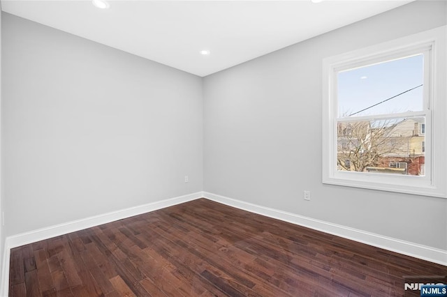 empty room with recessed lighting, dark wood-type flooring, and baseboards