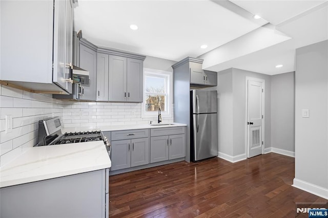 kitchen with stainless steel appliances, dark wood finished floors, a sink, and gray cabinets