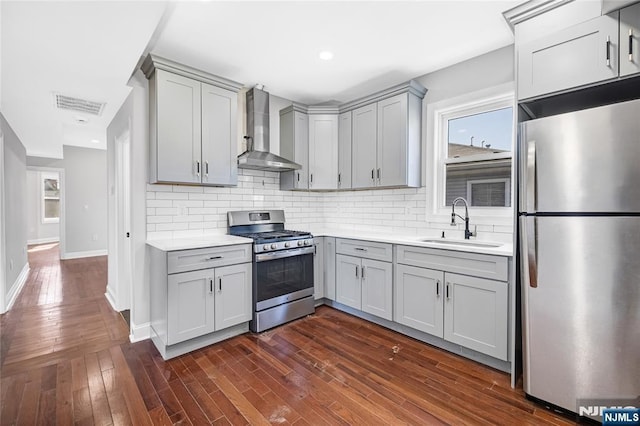 kitchen with wall chimney range hood, visible vents, gray cabinets, appliances with stainless steel finishes, and a sink