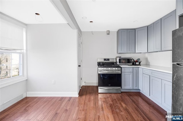kitchen featuring stainless steel appliances, gray cabinetry, light wood-style flooring, and baseboards