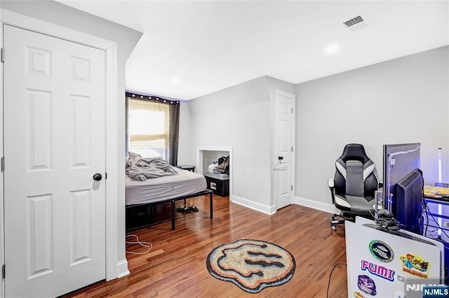 bedroom featuring visible vents, baseboards, and wood finished floors