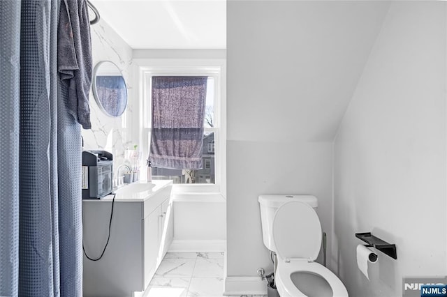 bathroom featuring toilet, marble finish floor, vanity, and baseboards