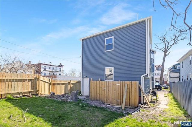 rear view of house featuring fence and a lawn