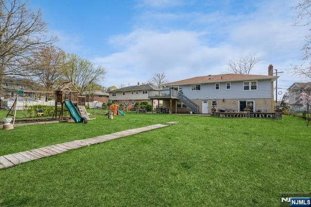 rear view of house featuring a lawn, a chimney, fence, a playground, and stairs