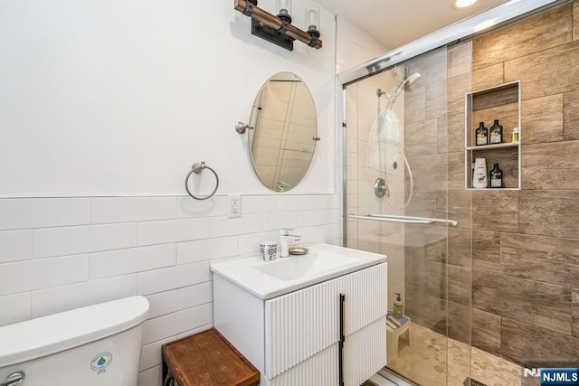 bathroom with tile walls, toilet, and a shower stall