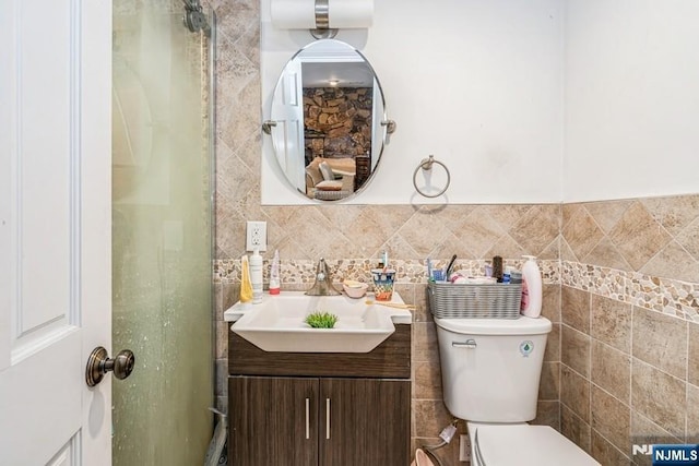 bathroom with tile walls, toilet, and vanity