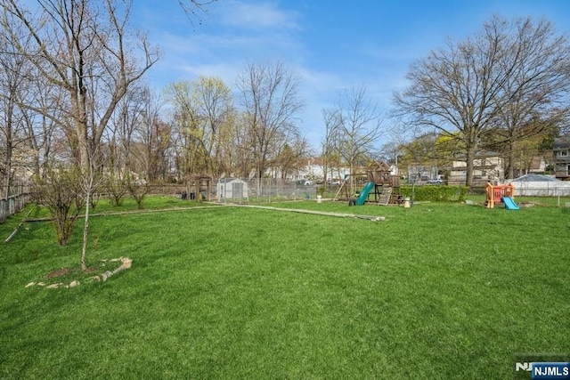 view of yard featuring playground community and fence