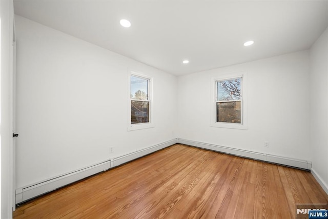 spare room featuring recessed lighting, baseboard heating, light wood-type flooring, and baseboards