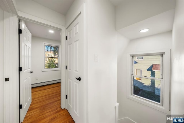 hall featuring light wood-style flooring, recessed lighting, and a baseboard heating unit
