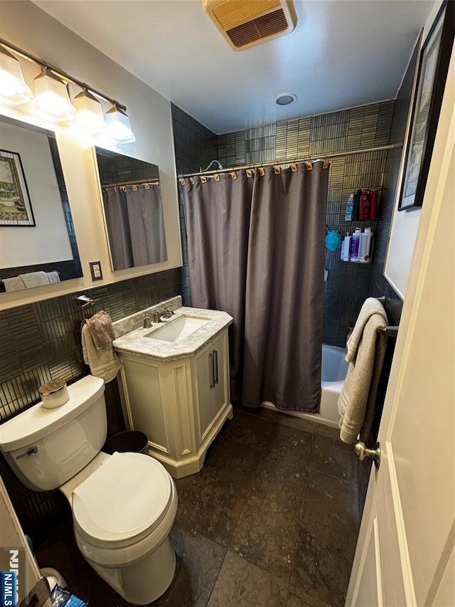 full bathroom featuring vanity, visible vents, toilet, tile walls, and shower / bath combo with shower curtain