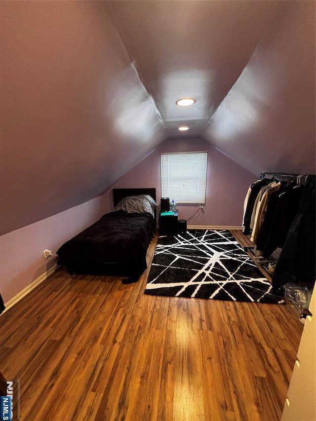 bedroom with wood finished floors, baseboards, and lofted ceiling