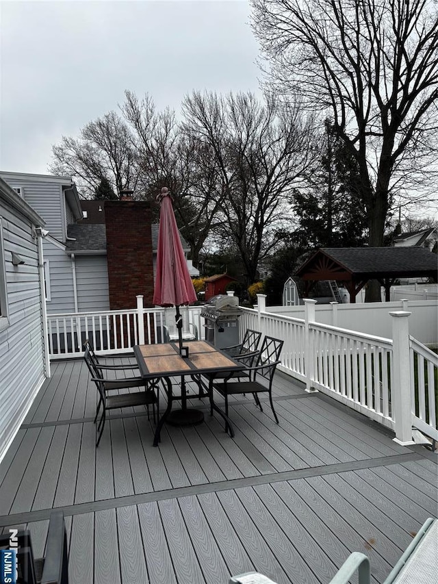 wooden deck featuring grilling area, outdoor dining space, and fence