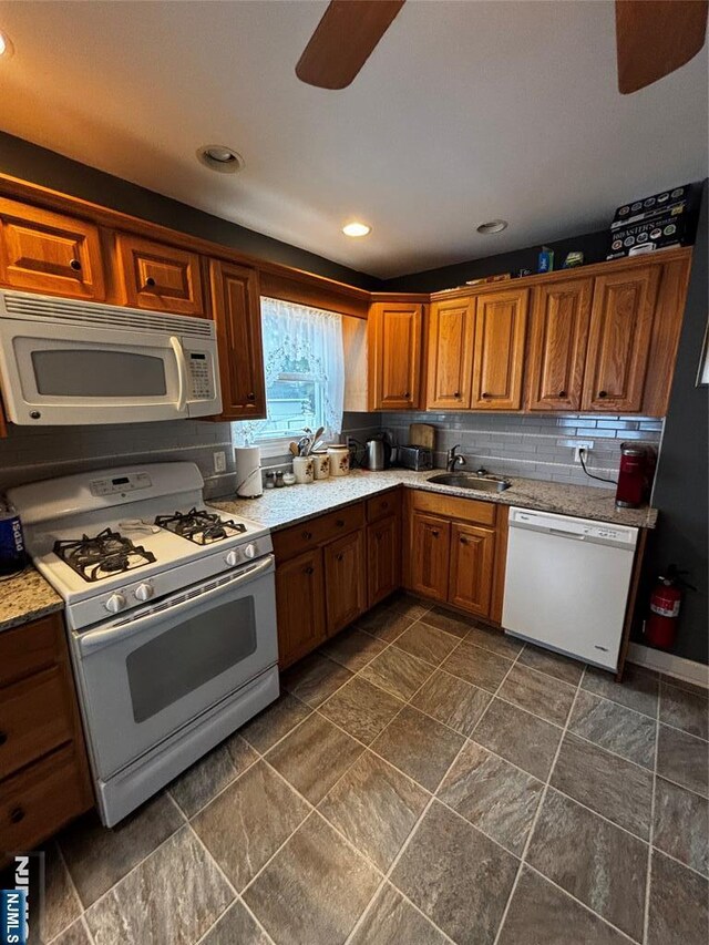 kitchen with ceiling fan, white appliances, light countertops, a sink, and brown cabinets