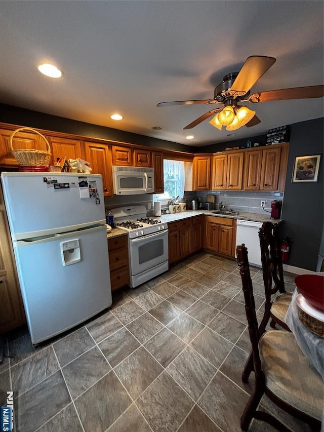 kitchen with white appliances, light countertops, brown cabinets, ceiling fan, and a sink
