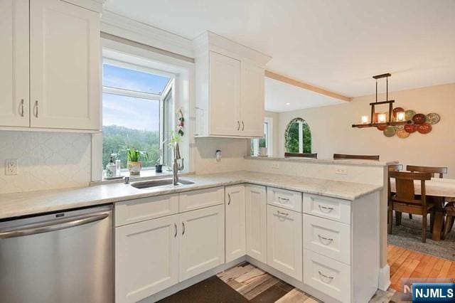 kitchen featuring a peninsula, white cabinets, light wood finished floors, dishwasher, and a sink