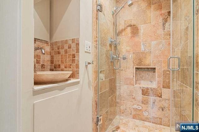 bathroom featuring a sink, tile walls, and a shower stall