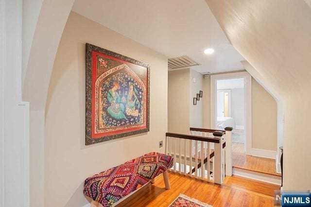 corridor with recessed lighting, an upstairs landing, and wood finished floors
